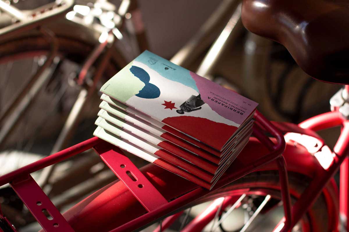 Berripaperas apiladas sobre la rejilla de una bicicleta roja.
